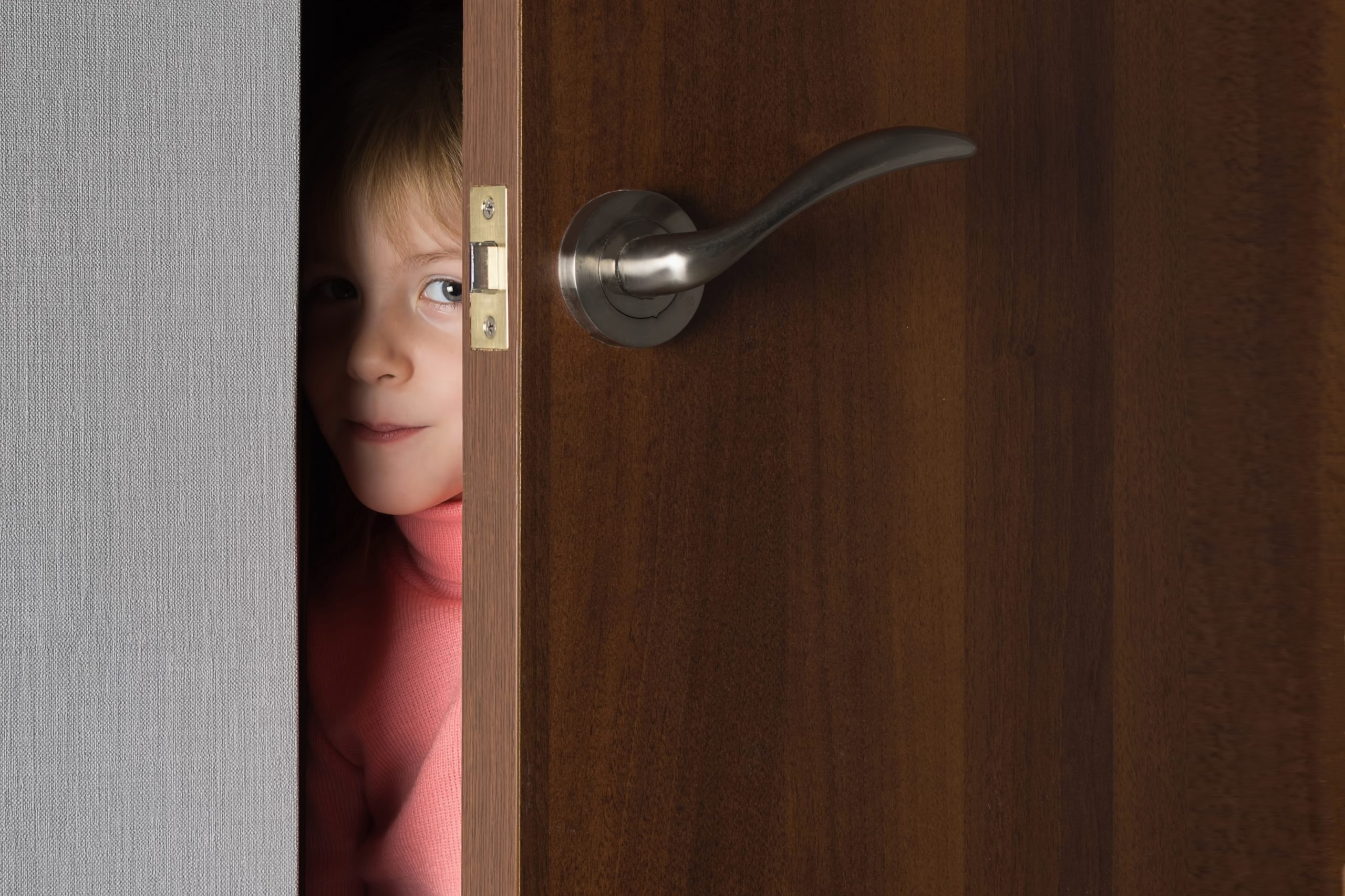 This is a picture of A child, a little girl, looks out from the ajar door of the room for an article called Exploit Your Competitive Intelligence Discoveries by Octopus Competitive Intelligence Competitor Analysis