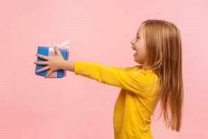 This is a picture of a Girl offering a present representing the article Outsourcing Competitive Intelligence is a good idea by Octopus Competitive Intelligence beat competitors, increase sales, solve problems, Competitor Analysis. Why does your sales team need competitive intelligence?