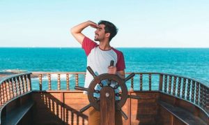 This is a picture of a man look out to sea while sailing a boat 11 questions to make Competitive Intelligence a success By Octopus Competitive Intelligence beat competitors, increase sales, solve problems, Competitor Analysis How to conduct research on competitors to define, compete and crush them