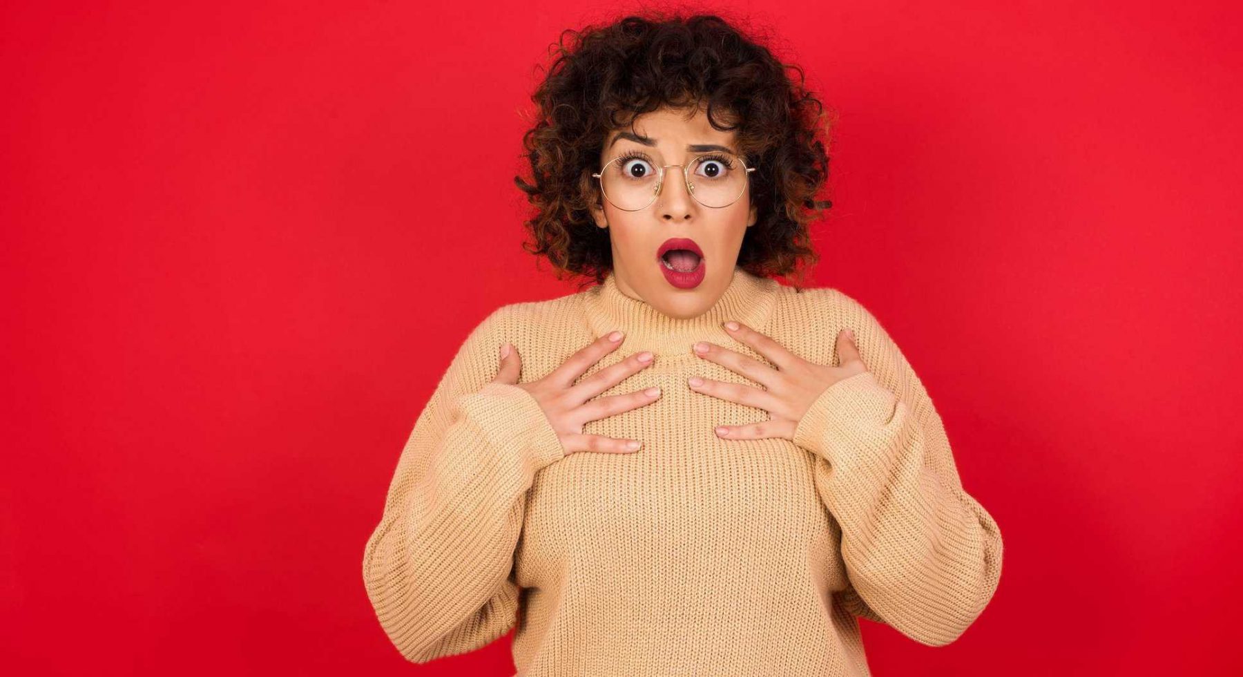 This is a picture of a women MODELO keeps hands on chest feeling shocked and scared, mouth widely opened, stares at camera saying: Who, me? for an article called who does competitive market analysis Octopus Competitive Intelligence and Competitor Analysis company