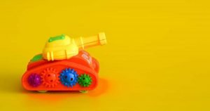 This is a picture of a Toy tank isolated on a yellow background for an article called Competitive Intelligence battlecards a powerful weapon to help you fight off your competitors by Octopus Competitive Intelligence and Competitor Analysis