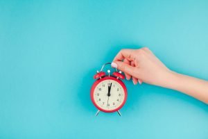 this is an image of a Woman hand holding the red vintage alarm clock taking time away for an article called Competitive Analysis is Essential For Any Business so Take Time to Research by Octopus Competitive Intelligence consulting agency research your competitors. When Should an Investigation Become a Legal Case