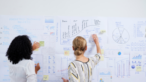 This is an image of two people strategising for an article called How Market Research Can Help Guide Your Market Entry Strategy by octopus competitive intelligence agency octopus competitive intelligence solutions. Market Entry Strategy: How Competitive Intelligence Research Helps